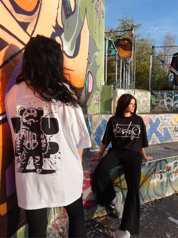 Zwei Personen, eine trägt von forne schwarzes Oversize-Shirt, eine von hinten und  trägt weißes Shirt mit Rückenprint, casual Streetstyle, Unisex